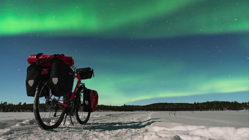 Time-lapse of northern lights with a bicycle sitting in the foreground