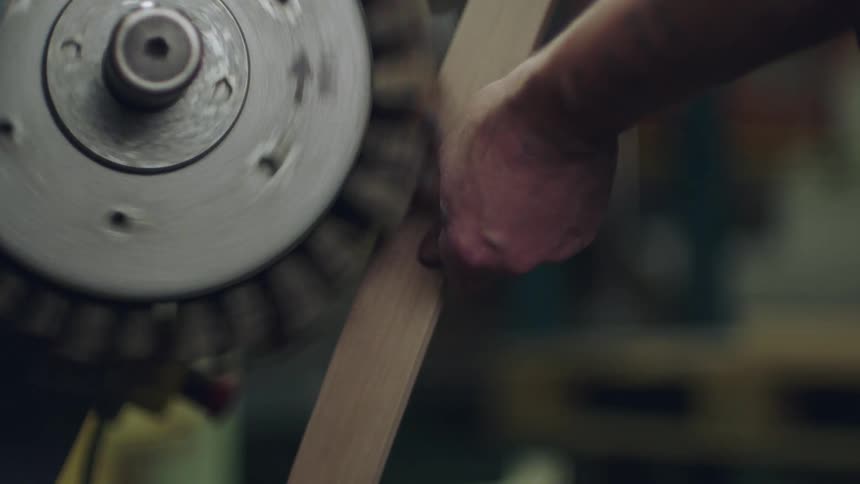 A mans hands running a piece of wood through a table saw