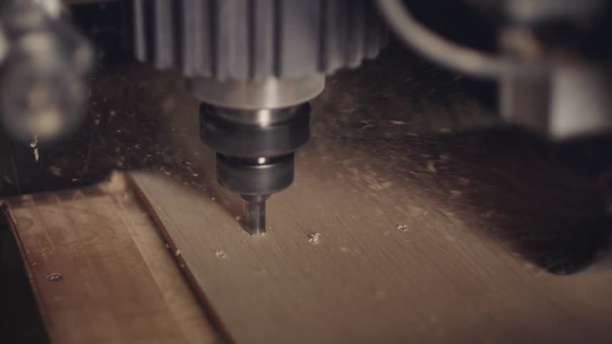 Closeup of a machine drilling into a wooden board