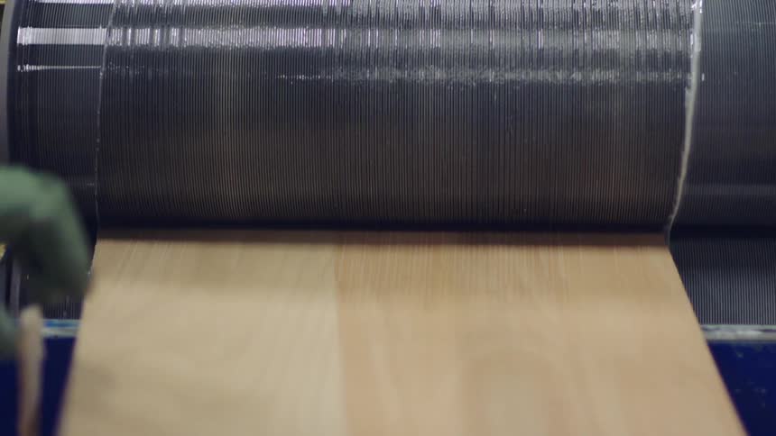 Factory worker pulls sheet from between sticky rollers