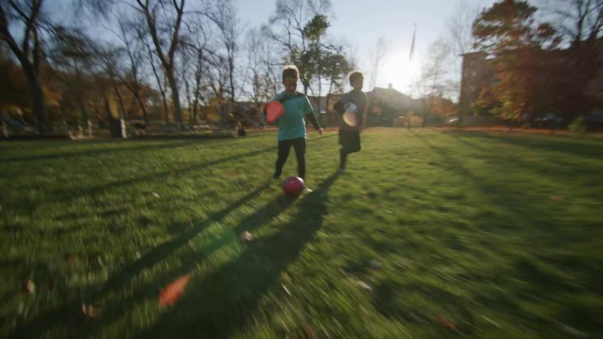 Two kids enthusiastically playing football on the field