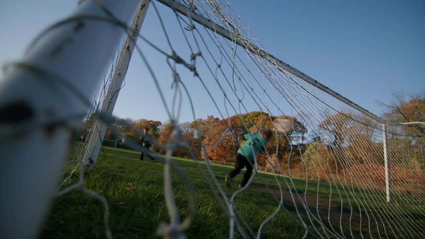 Boy scoring a goal against his friend who is the goalkeeper