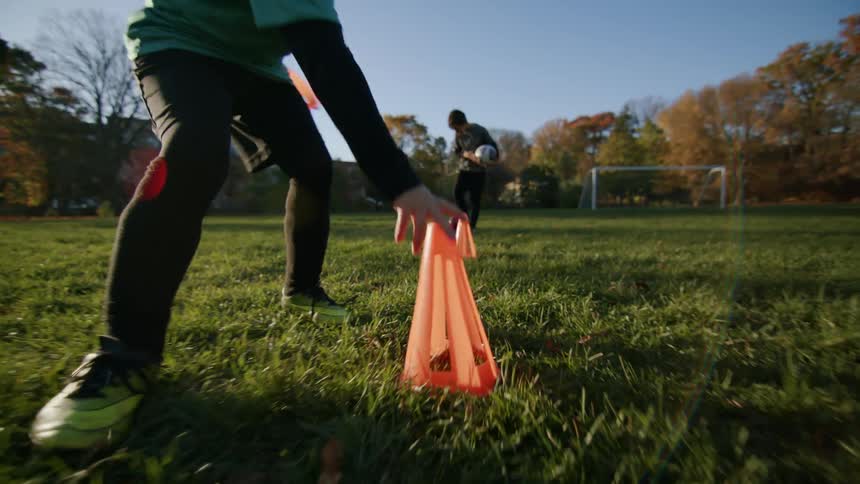 A boy sets up soccer cones on the soccer field