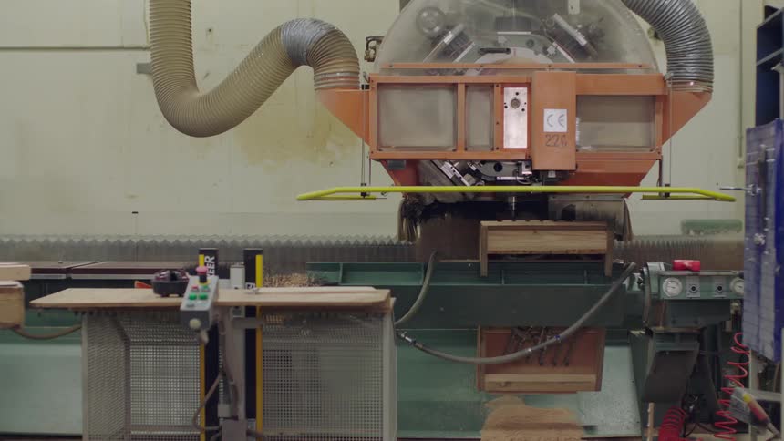 Machine inside a factory cutting through a wooden board