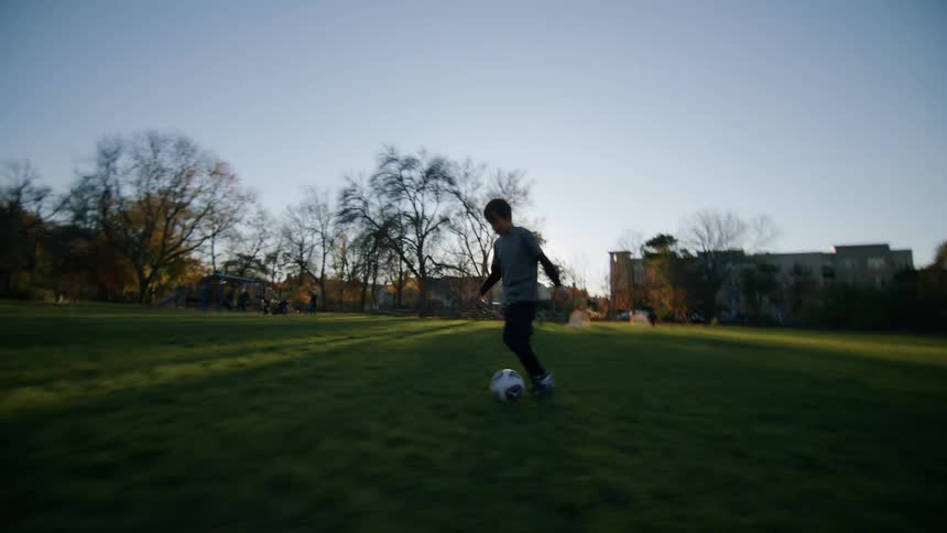 Boy running while playing with a ball on a grassy field