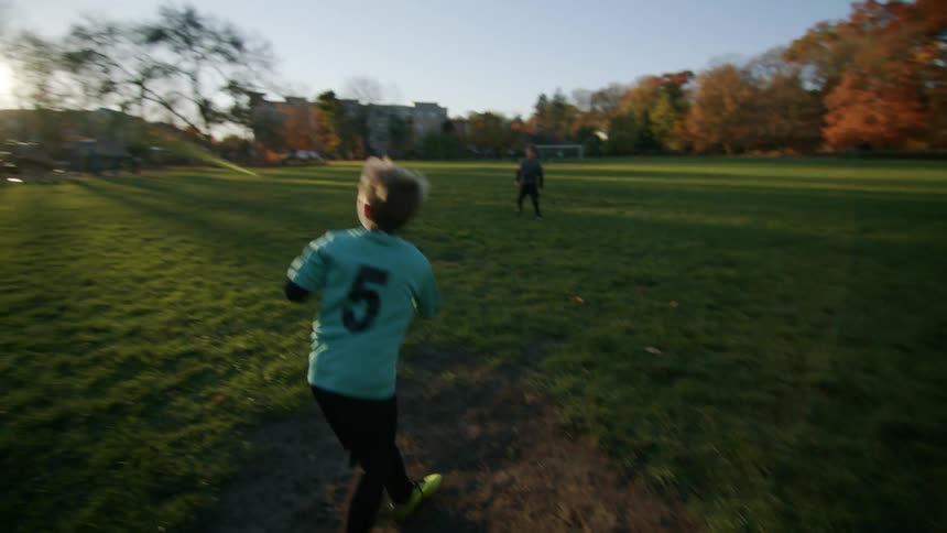 Boy kicking a ball with his friend on a grassy field