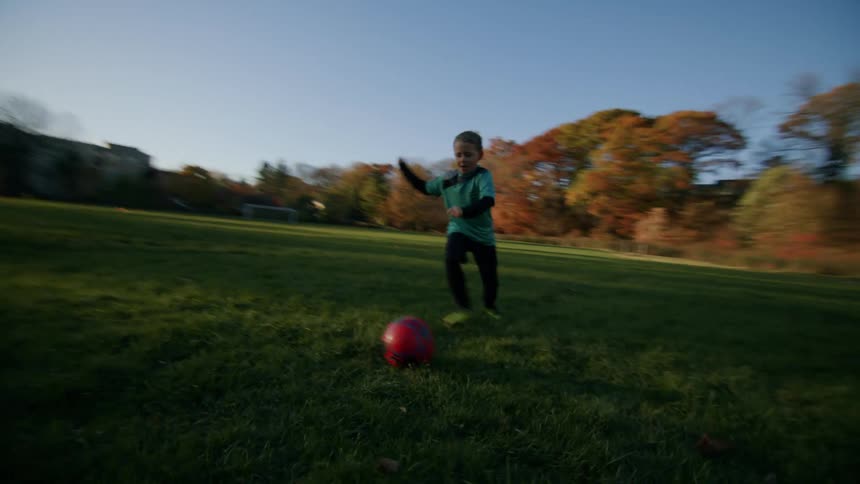 A boy dribbles the soccer ball on the soccer field then takes a shot and scores defeating the goalkeeper
