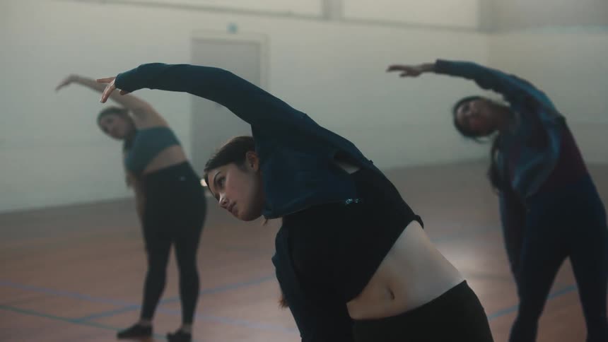 Three women stretch together in studio