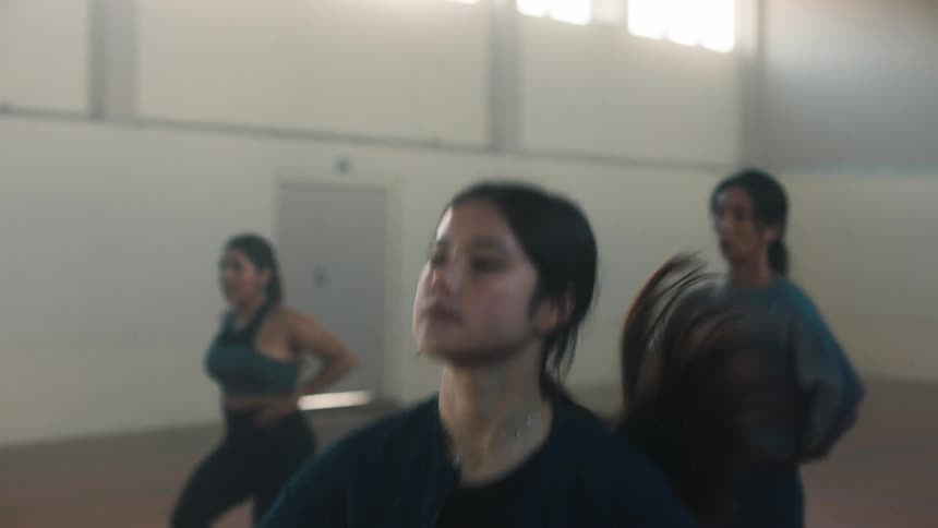 Young women on an indoor court with hands on their waists jumping in a cardio workout