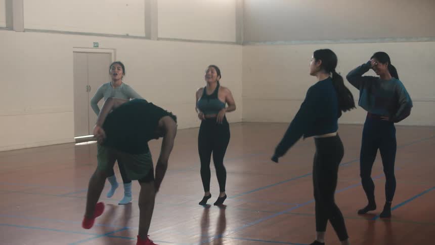 A male fitness instructor leads a workout and then high fives the participants