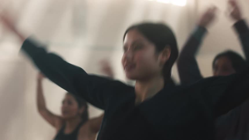 Women doing jumping jacks in an indoor setting