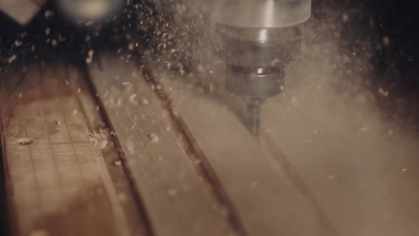 An iron machine rotating cutting wood and several particles flying
