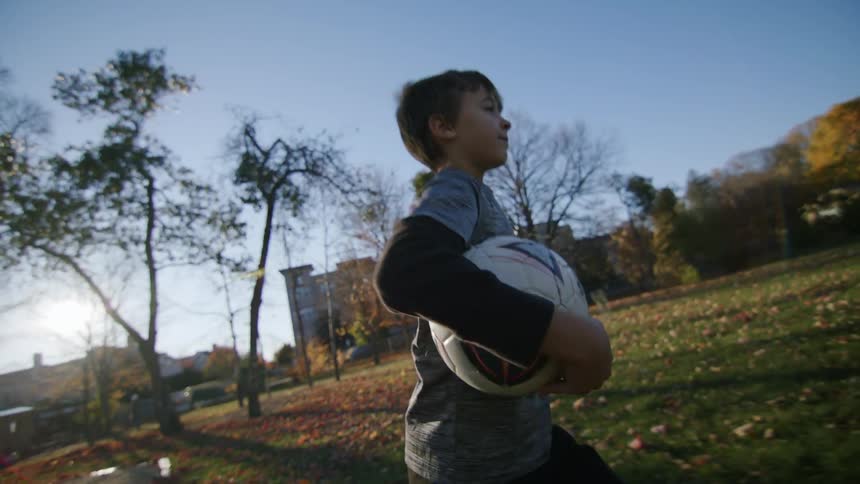 Two young boys walk though a field with a soccer ball