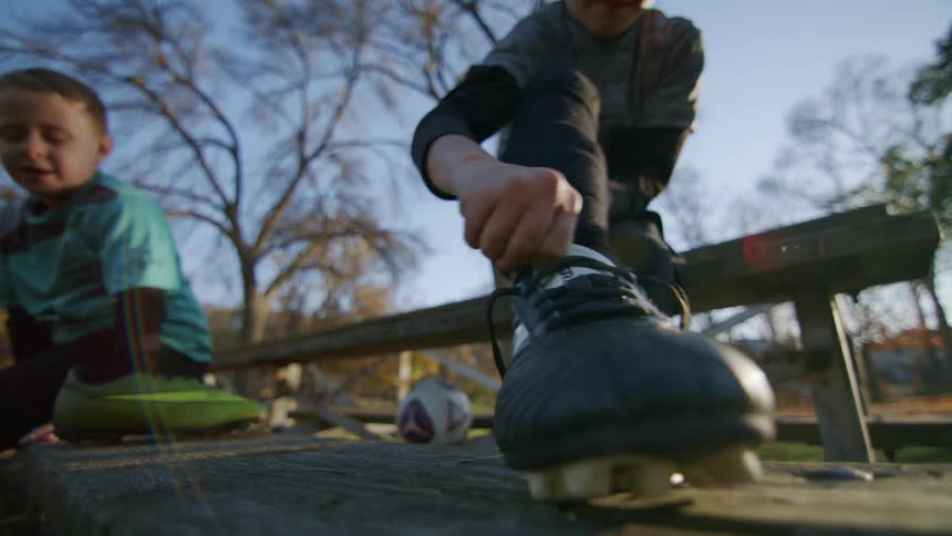 A boy tying his football boot laces