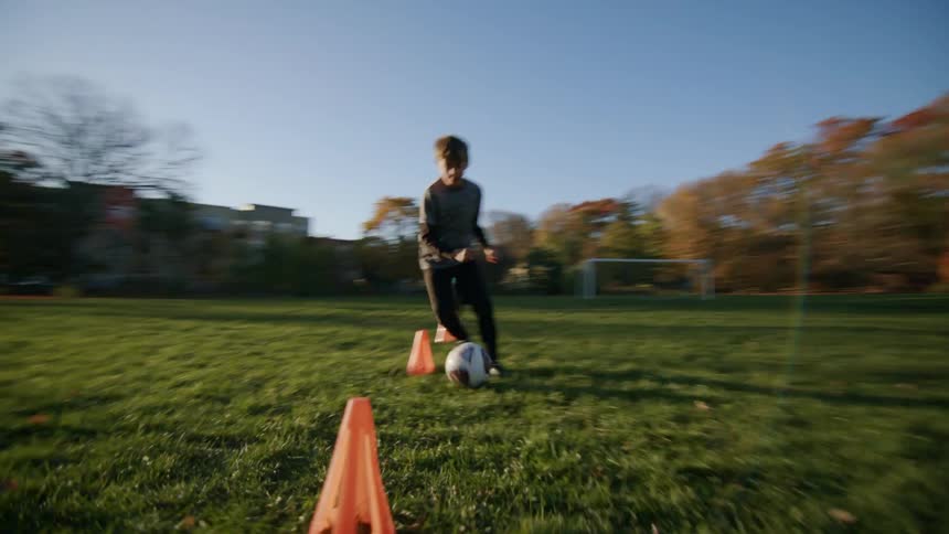 Boy practicing soccer on the field at morning
