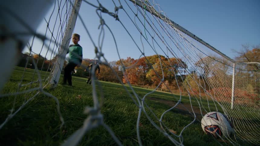 The boy confidently shoots and scores a goal while playing soccer in the field