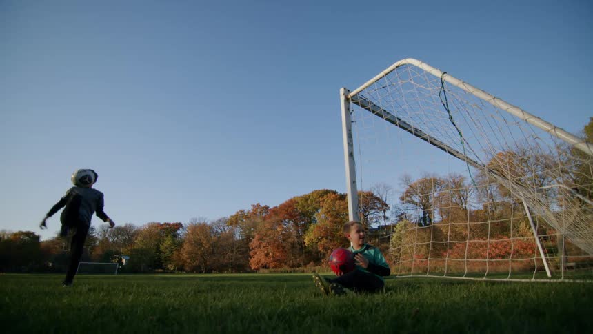 Two kids enthusiastically playing football on the field