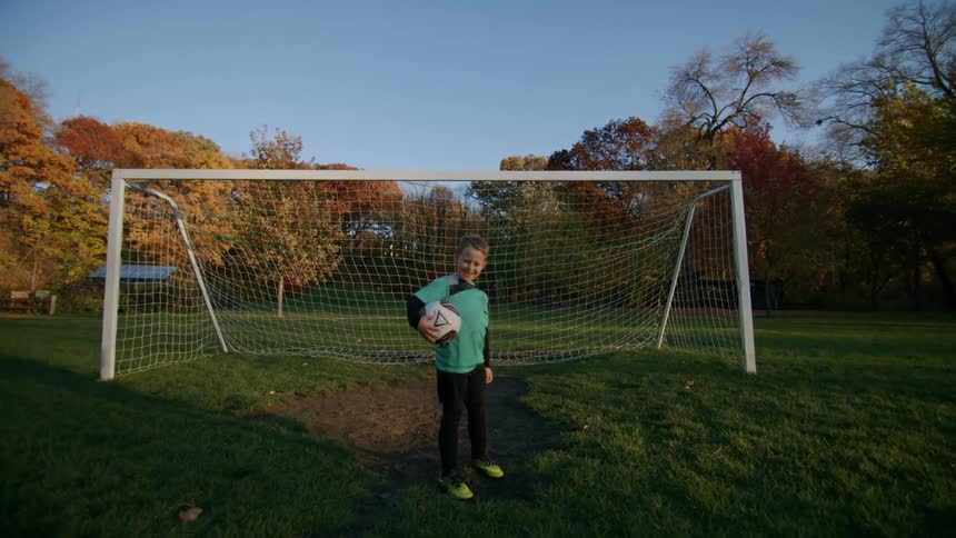 A player with the soccer ball in his arms standing in front of the goal