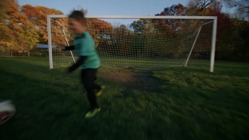 Boy facing a soccer goal playing with a ball