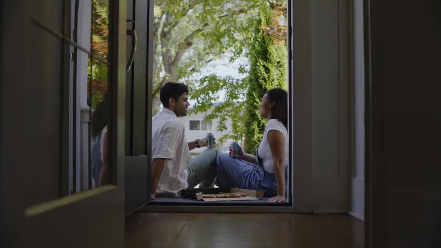 A man and woman drink a beer on the porch
