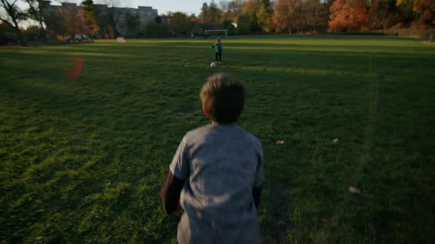 Two children are playing soccer in a field on a clear autumn day