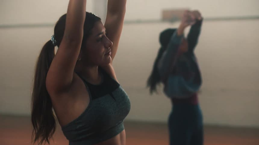 Two women are standing and stretching their arms