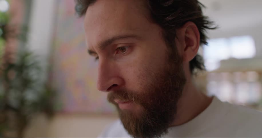Close up of a young bearded man sitting in the lobby of a hotel
