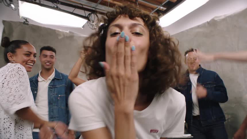 Woman blows a kiss while a group of happy people have fun dancing in a studio