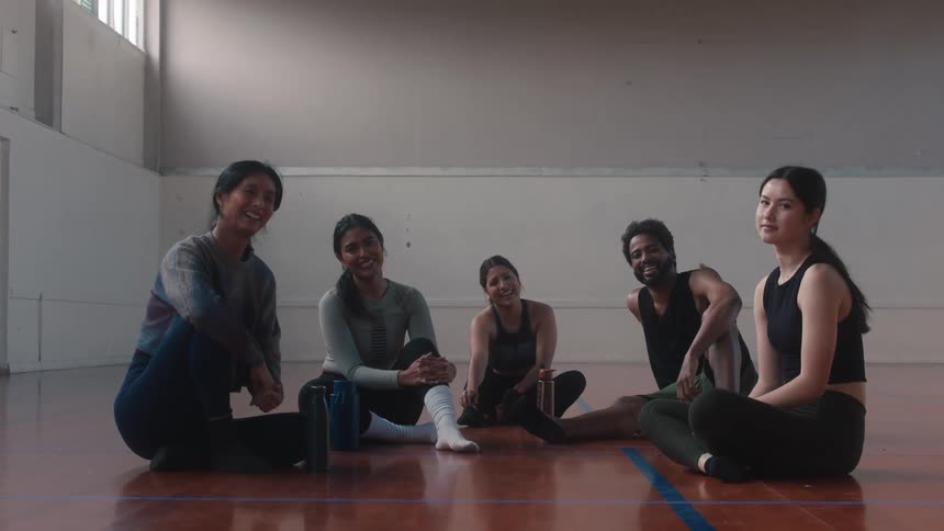 Dancers sitting on a court smiling for the photo