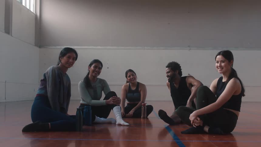 A group of dancers sitting on the floor laughing