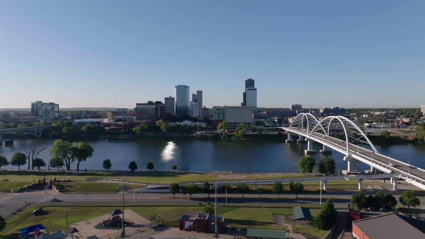 Aerial view of a bridge spanning over a river with the city skyline in the background