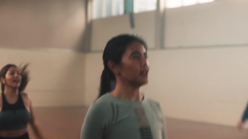 Group of girls doing jumping jacks in a gymnasium