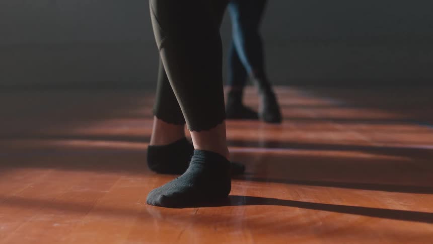 Close up of a ballet dancers legs with black leggings and socks dancing