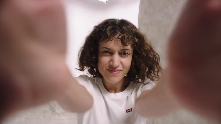 A model sitting on the floor in a well lit area and shakes the camera with her hands photography white cyc denim levi jeans whip pan transition