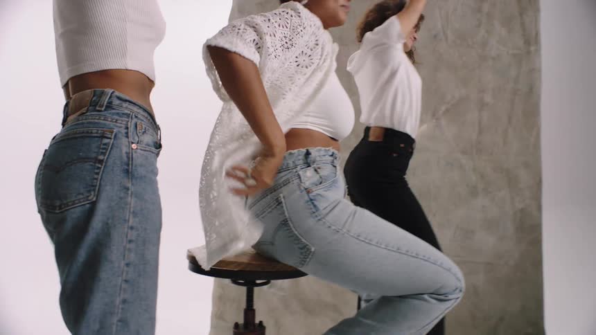 Three women dancing and modeling in white tops and jeans