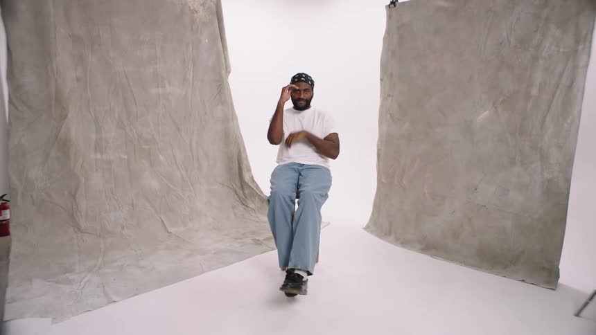 Man sitting on stool in photography white cyc studio smiles while changing poses denim blue collar