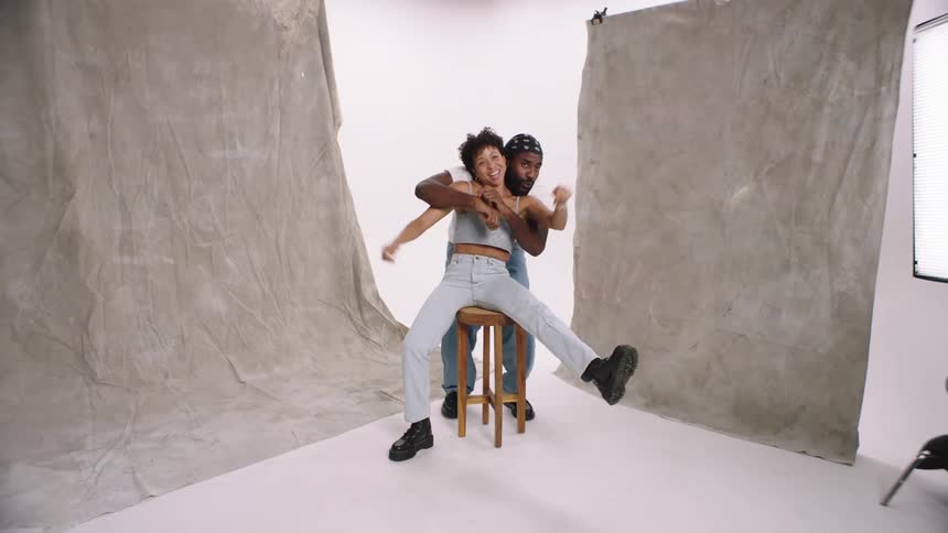 Man and woman in a white cyc studio dancing while modeling models being quirky