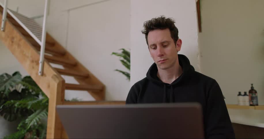 A man in front of his laptop in his livingroom