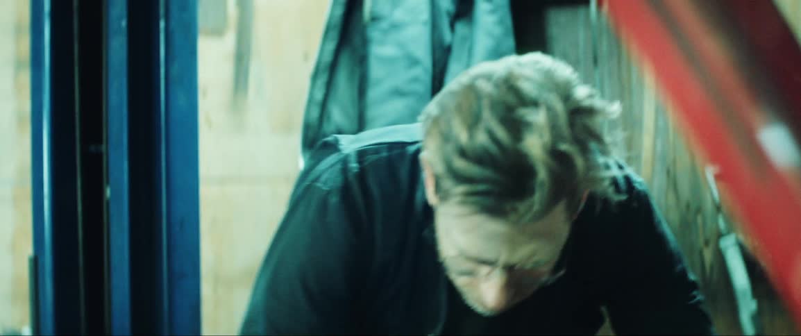 A man lifts the hood of a sports car and looks at the engine