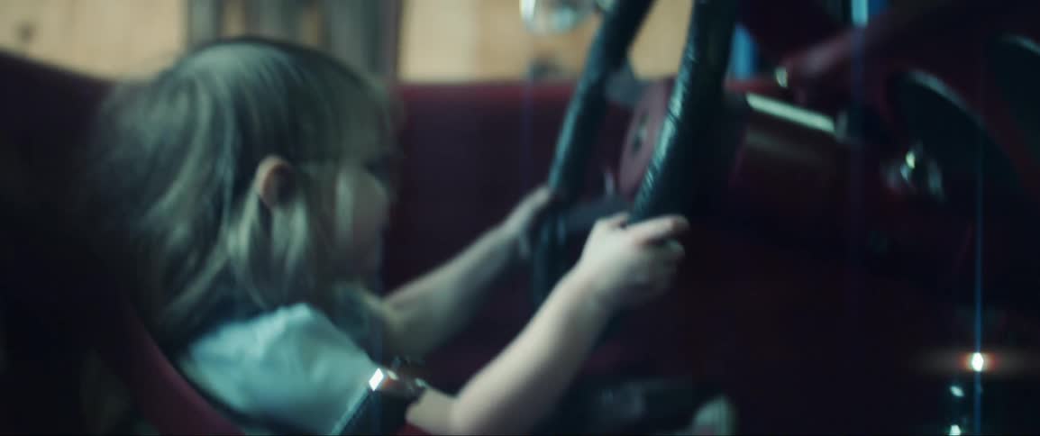 Girl sitting on the seat and with one hand on the steering wheel of the car