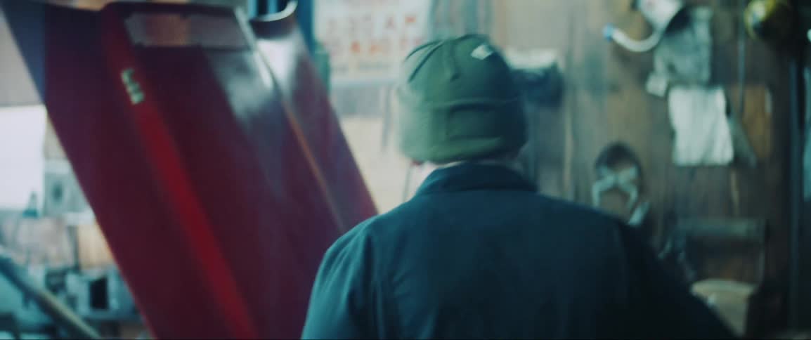 Man in the workshop putting on a jacket and a red classic sports car next to him
