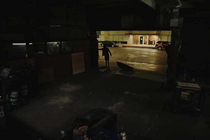 Person opening the gate of a workshop and turning on its lights