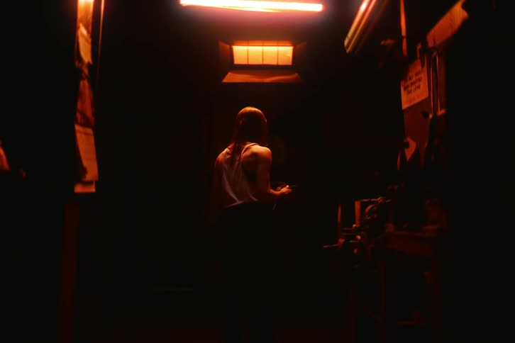 Woman inside a darkroom with red light putting on a denim jacket