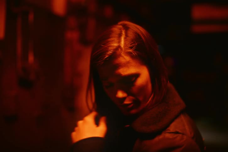 A woman putting on a coat in a room with red light