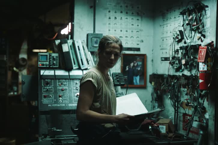 A woman reading a report in a factory at night
