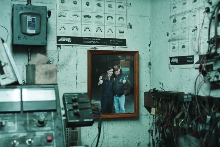 Woman inside an office looking at a photo of herself with her father on the wall