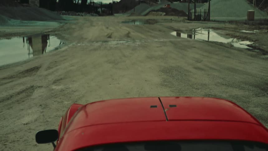 A red car stopped on a gravel road