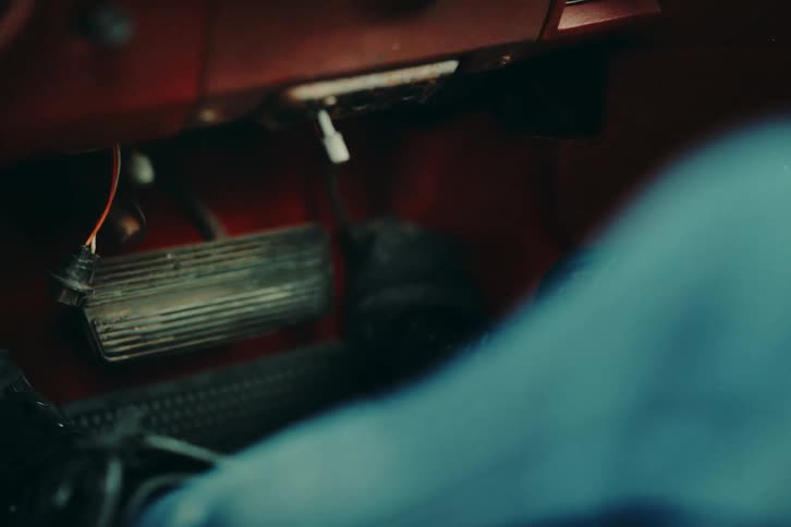 Feet in black leather boots stepping on the cars accelerator