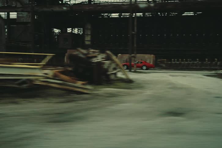 A sports car speeding across a junkyards dirt road