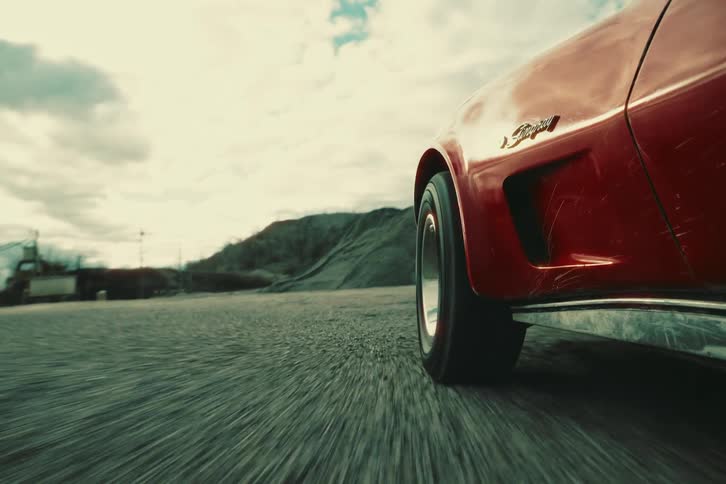 A red car skidding on a dirt road during the day